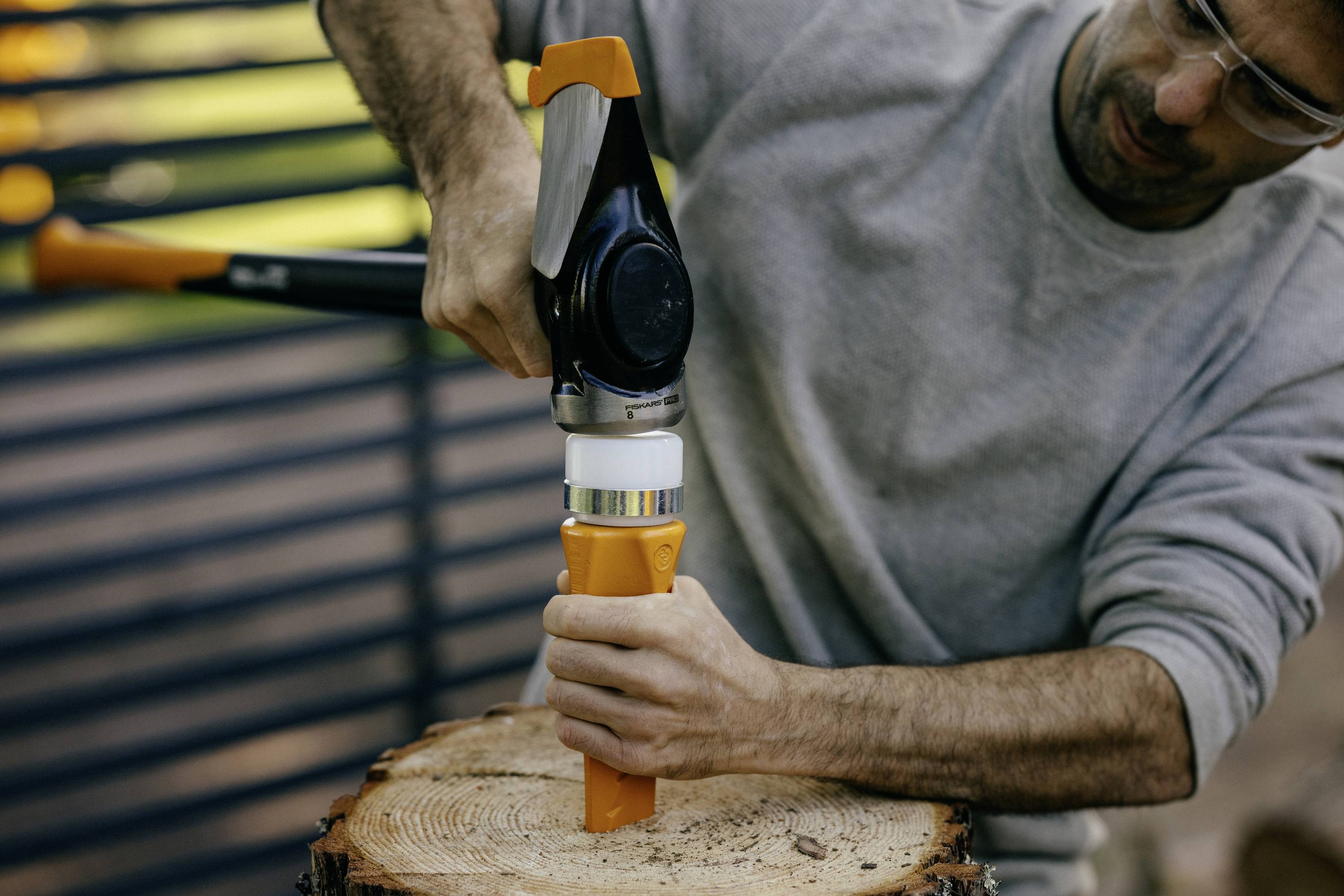 'A person is using a manual wood-splitting tool on a tree trunk outdoors.'
