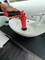 A hand uses a red plunger to unblock an oval basin in a modern bathroom.