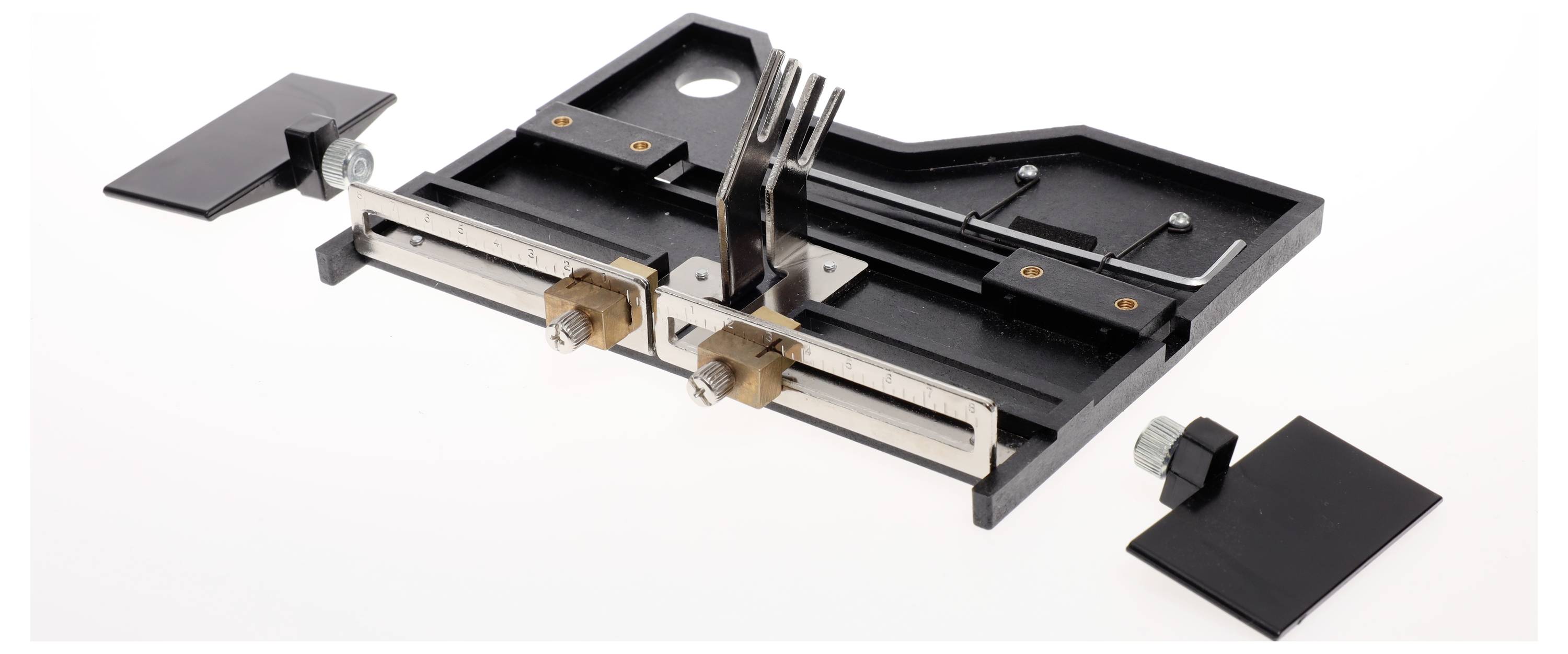 A black plastic board with metallic rails, adjustable clips and screws, likely a tool component or accessory.