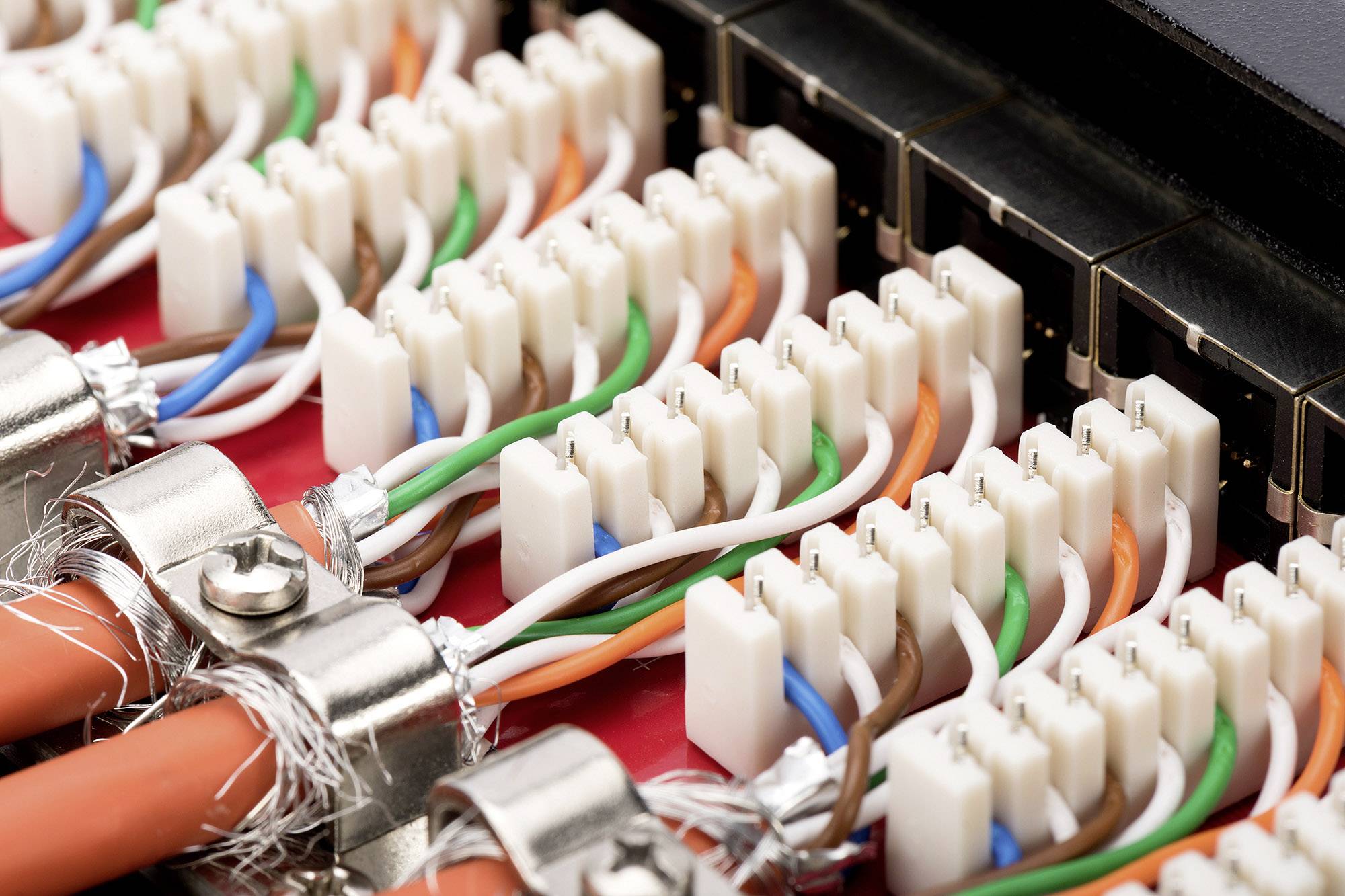 Close-up of a network cable panel with colourful Ethernet cables plugged into sockets.