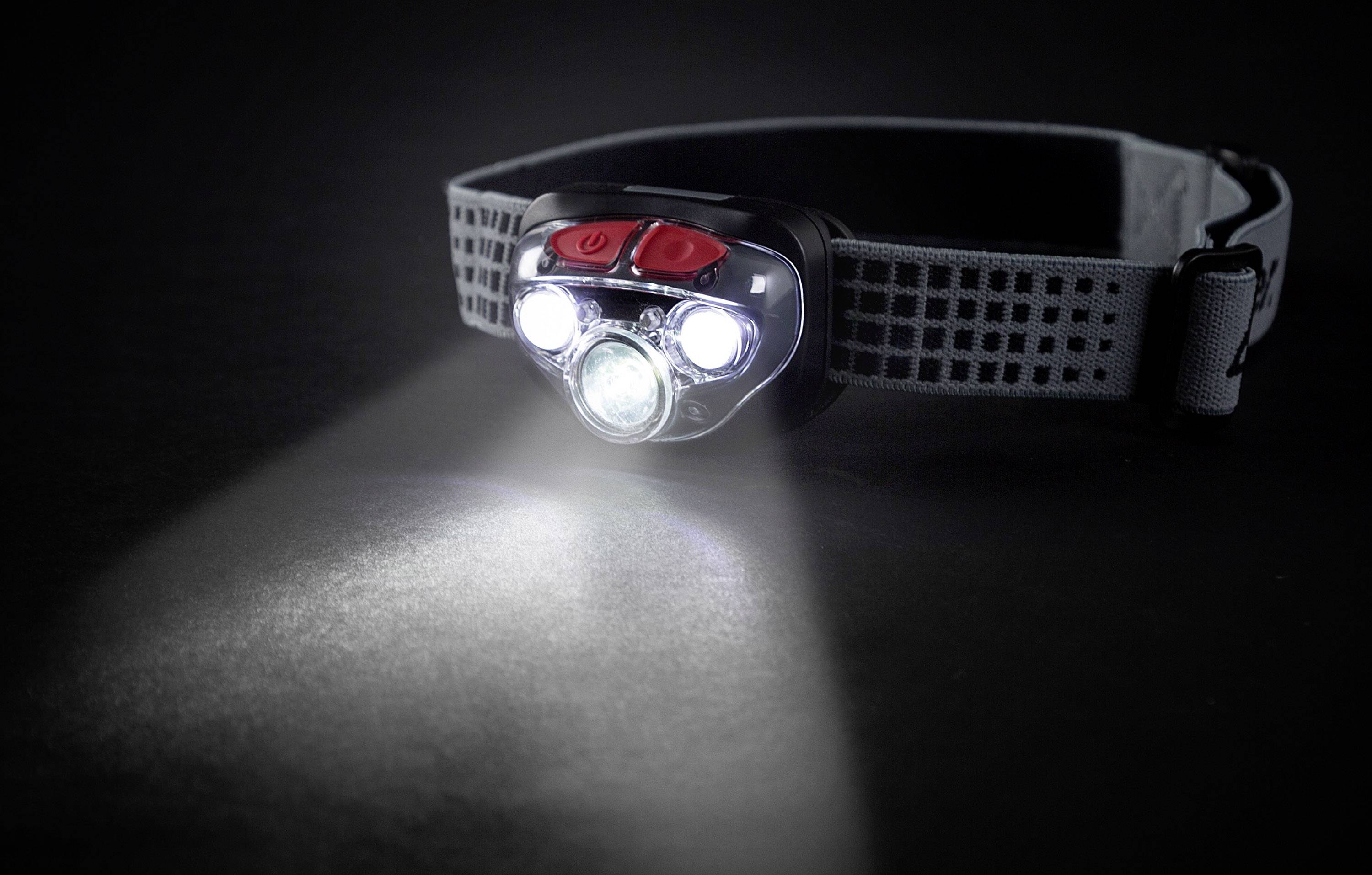 A head torch with multiple LEDs illuminates a dark room, with an adjustable strap.