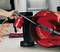A hand is using compressed air cleaner to clean the casing of an upturned lawnmower. A broom can be seen in the background.