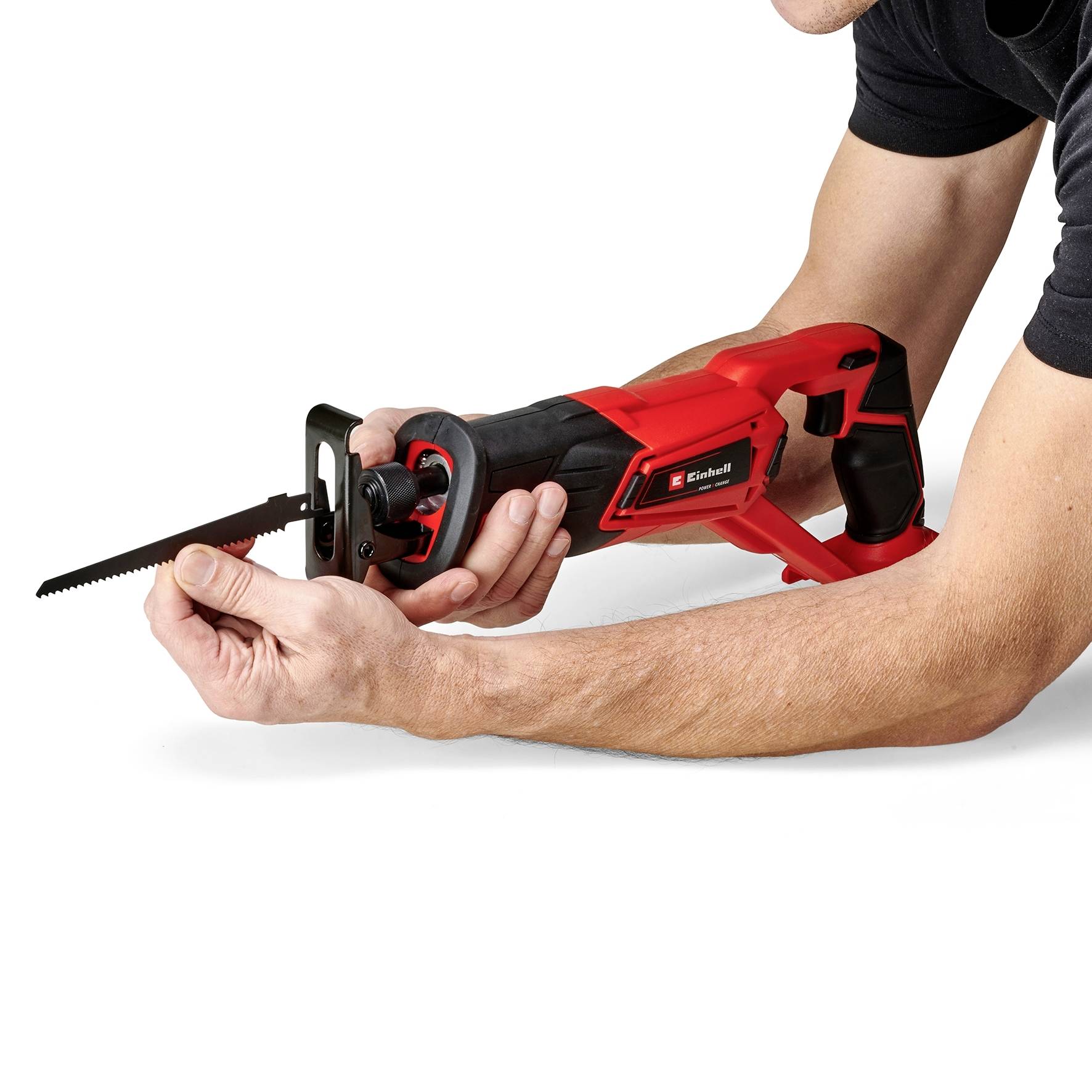 A person is holding a red saw. The saw has a long, thin saw blade and is being held with both hands.