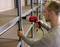 A person is using a red power drill to assemble a metal shelving unit in a storage room.