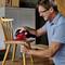 A man is sanding a wooden chair with an electric sander. He is wearing safety glasses and working with concentration.