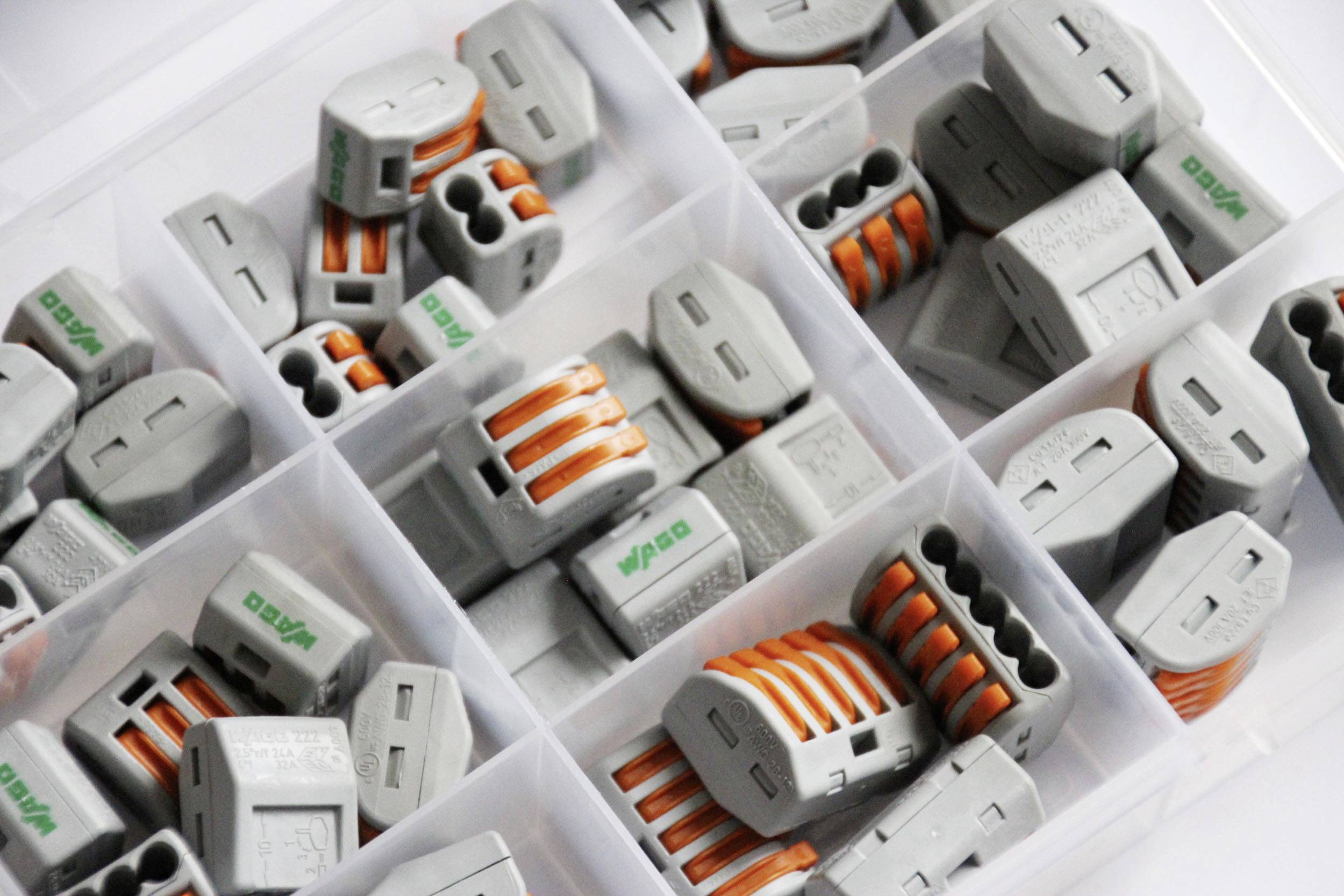 Grey and orange connection clips in a transparent storage box, arranged in separate compartments.