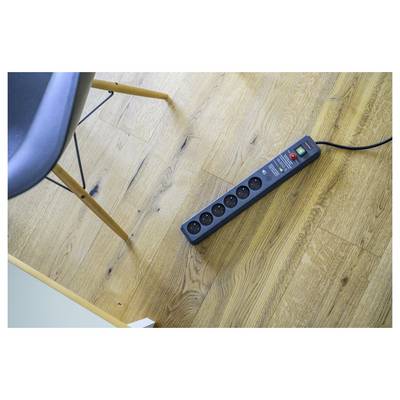 Power strip with six outlets and a switch lying on a wooden floor beside a chair leg.<br>