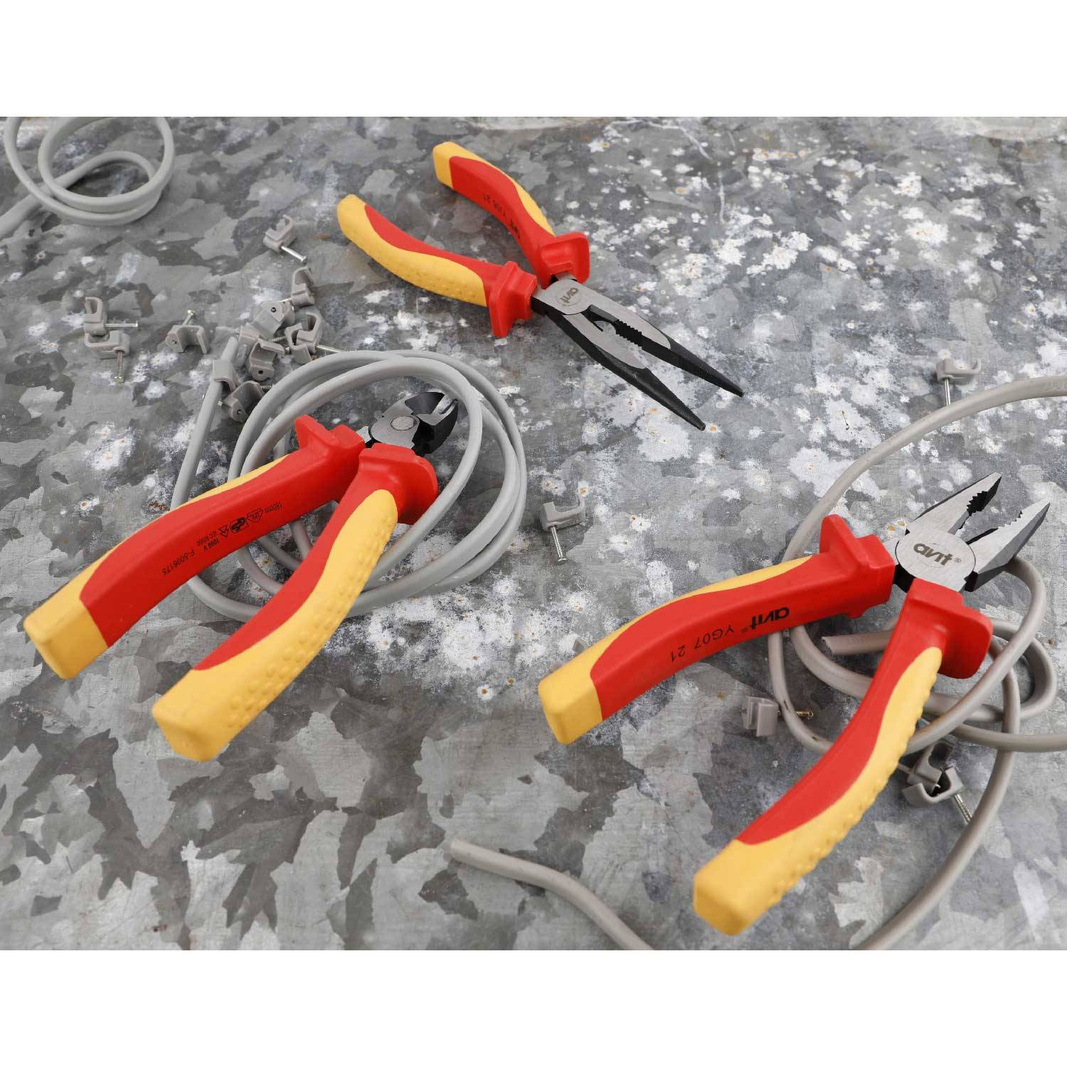 Two red pliers with yellow handles lie on a grey surface, surrounded by grey cables and screws.