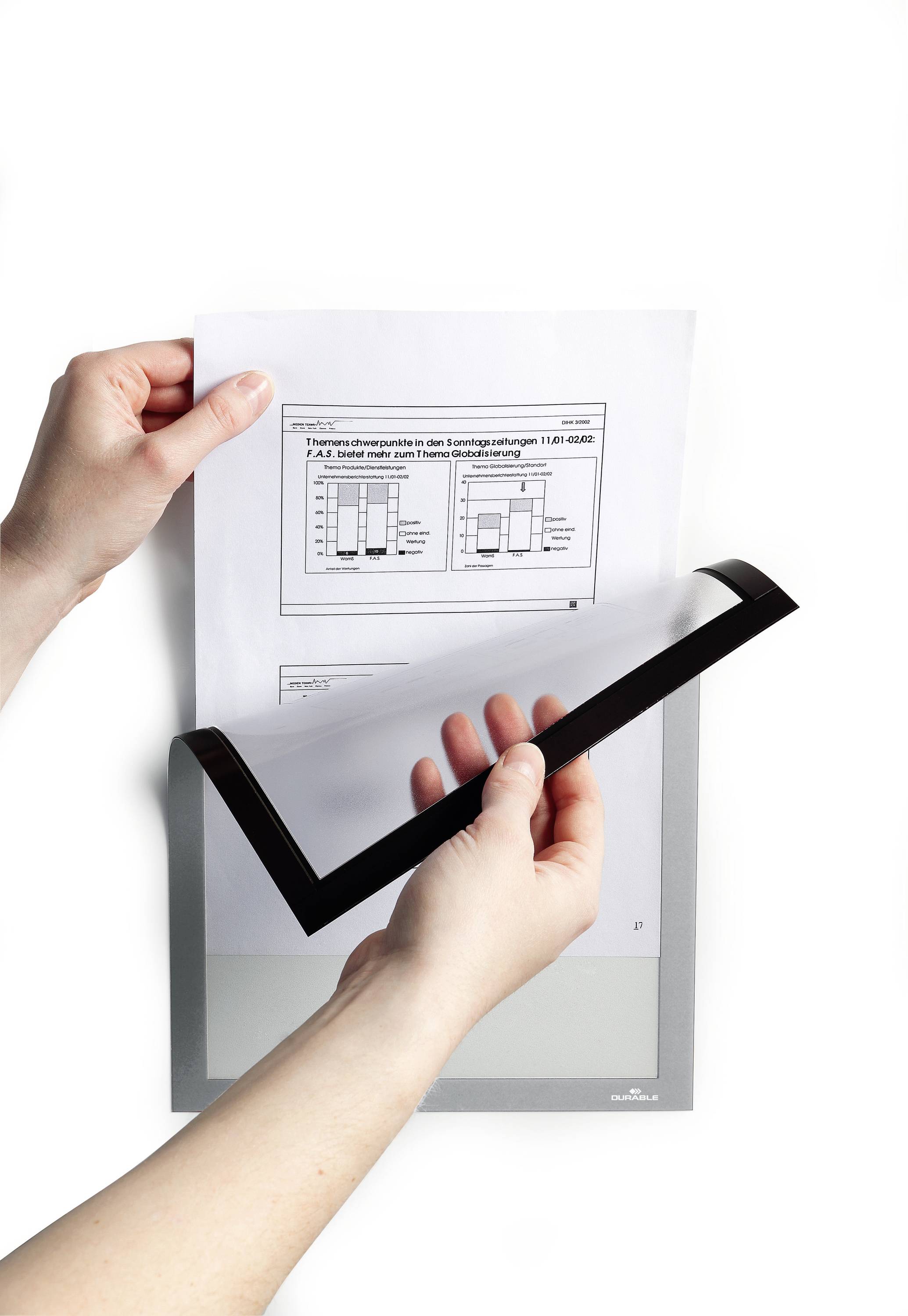 Two hands are holding a sheet of paper with a diagram covered by a transparent overlay. The diagram displays bar graphs.