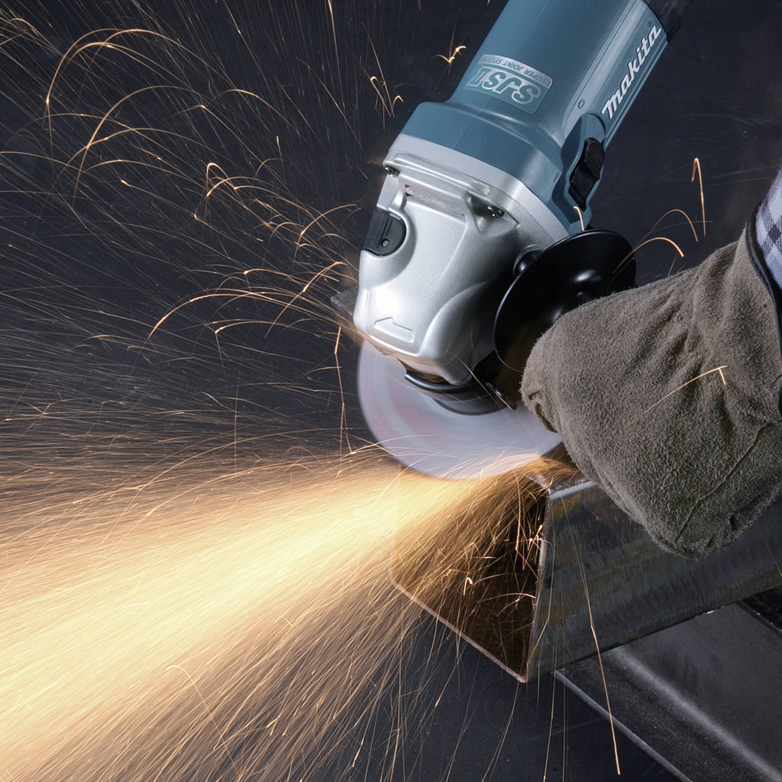 A person is grinding metal with an angle grinder, with sparks flying down to the bottom left. They are wearing protective gloves.