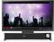 A large monitor displays a music video showing a crowd at a concert. Beneath it sits a Trust soundbar.
