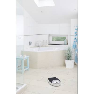 Modern bathroom with a bathtub, window, blue accents, potted plant, and personal scales on the floor.