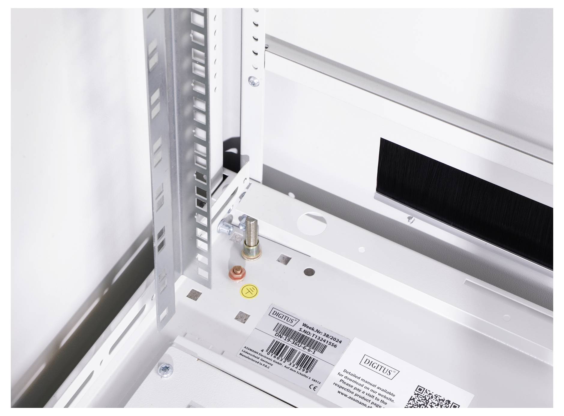 'Interior view of a white technical enclosure with metal frame and mounting elements. Labels and barcode are visible.'