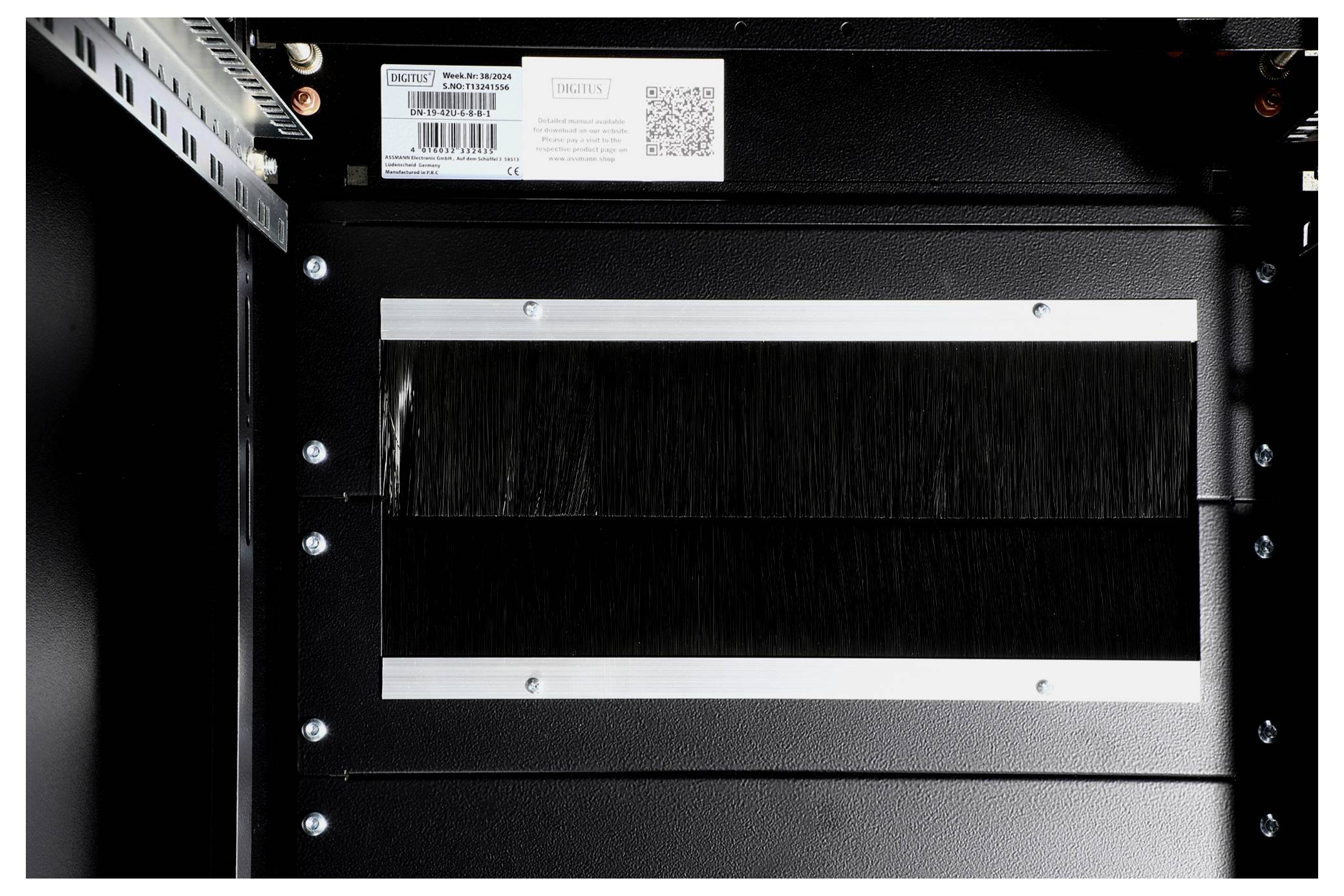 Metal plate with cable entry and brush seal in a black enclosure. On top, a nameplate with QR code and CE marking.