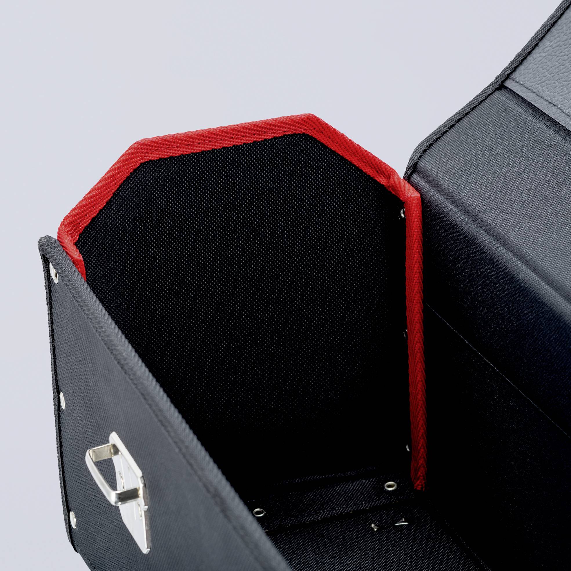 An open, black suitcase with a red interior lining. A silver clasp is visible on the left side.