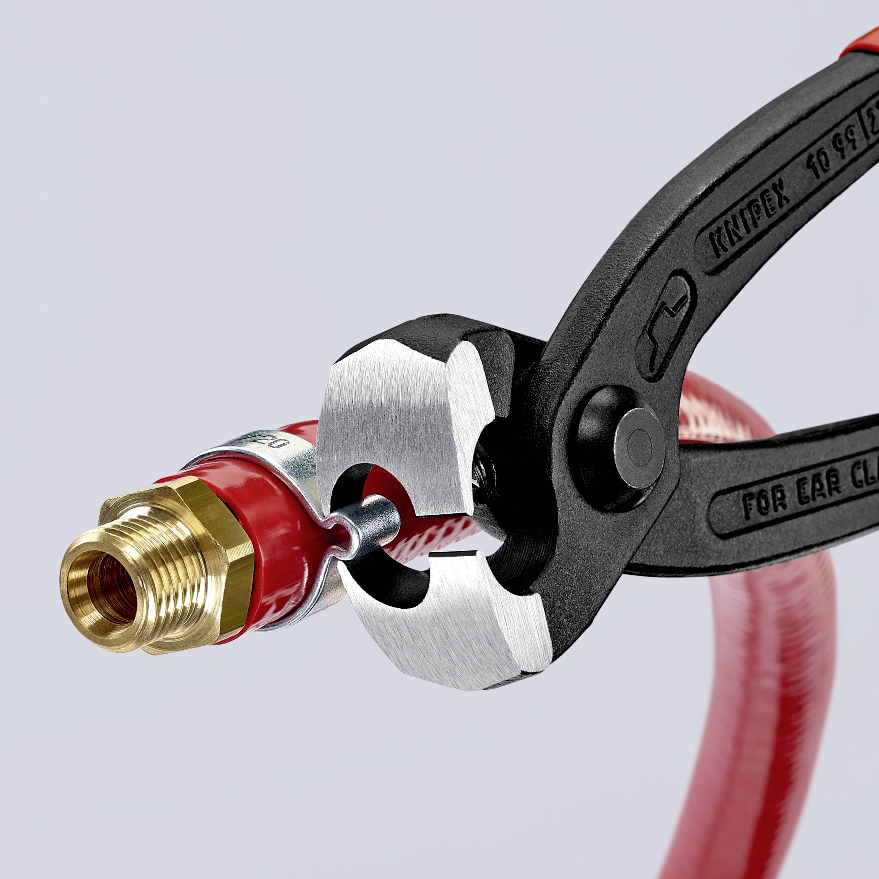 A pair of pliers is cutting a red hose near a brass fitting.