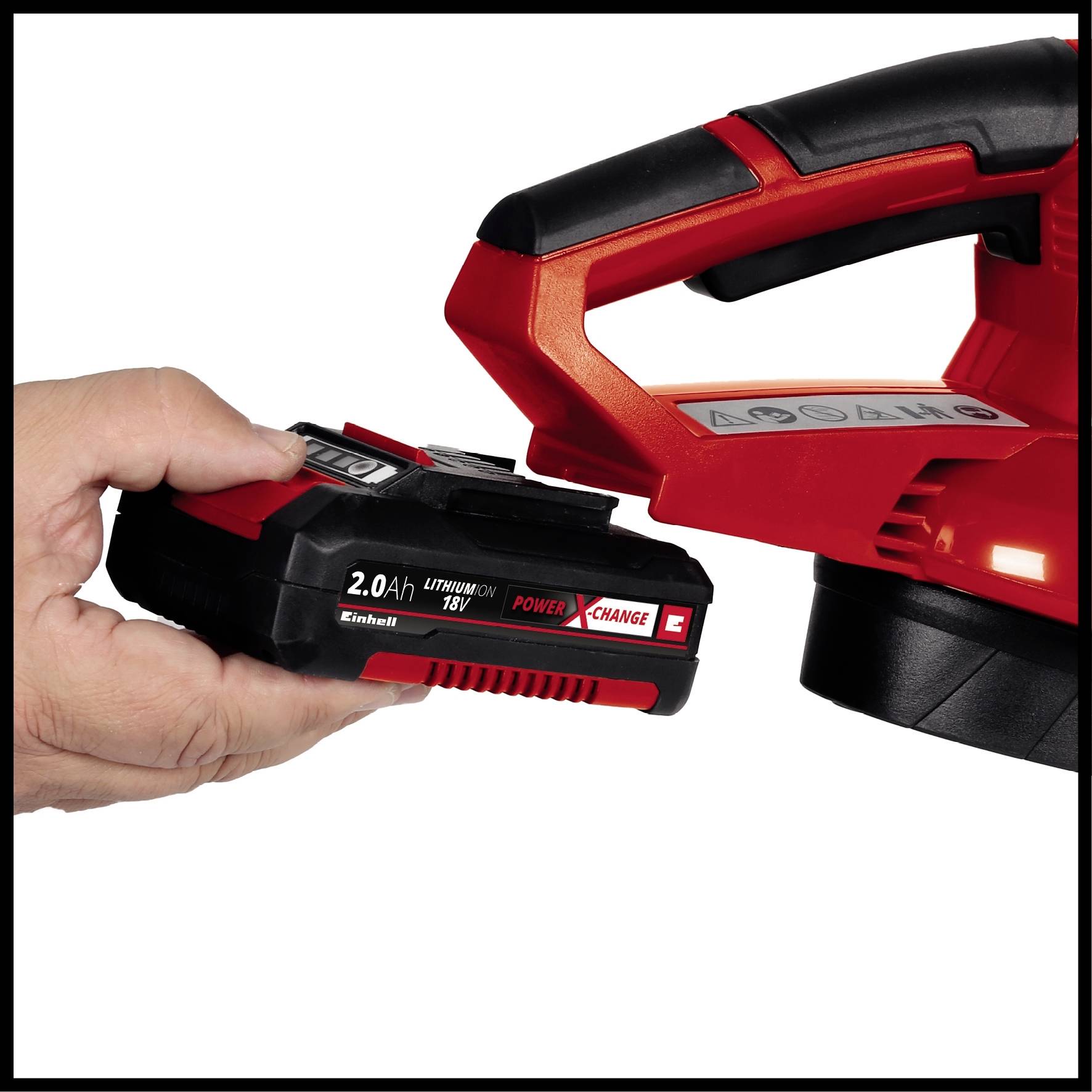 A hand is holding an 18V lithium-ion battery in front of a red electric power tool.