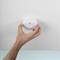 A hand is installing or testing a white smoke detector on a ceiling.