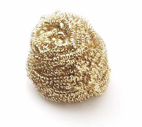 A golden metallic scrubber coiled into a tight ball, used for cleaning surfaces.