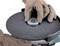 A person wearing gloves is changing the disc of a grinding machine. Focus is on caution and safety when handling the tool.