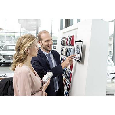 A man and a woman are examining a tablet in a car showroom, likely looking at car designs or colour samples, next to a colour palette.