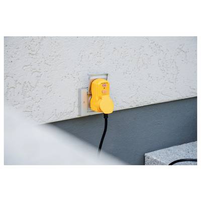 Yellow electrical outlet cover plugged into an exterior wall outlet on a stucco building.