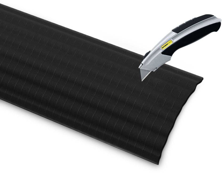 A craft knife cuts through a piece of black corrugated cardboard.