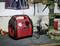 A red air compressor sits on a workbench in a workshop. Tools and a drill are visible in the background.