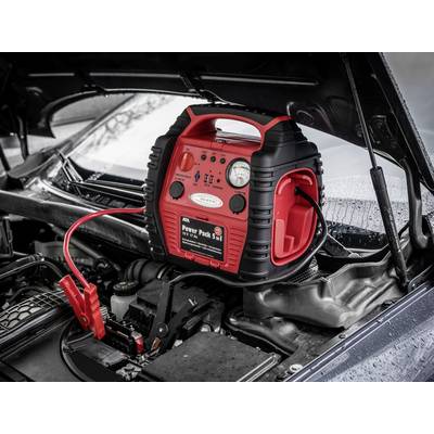 Jump start booster on a car battery under an open bonnet. Red and black cables with clamps are connected.