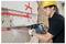 A construction worker wearing protective gear uses a power tool to cut through a concrete wall marked with red spray paint lines.