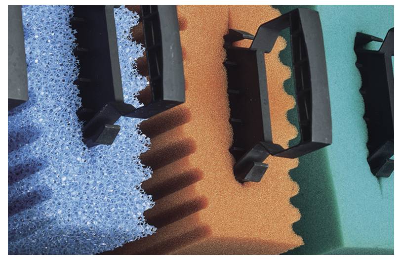 'Colorful textured sponges with black handles, overlapping; blue, orange, and green pads feature distinct patterns, emphasizing contrast.'