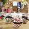 Four transparent Christmas baubles on a table, filled with various decorations such as pompoms and ribbons, with festive greetings.