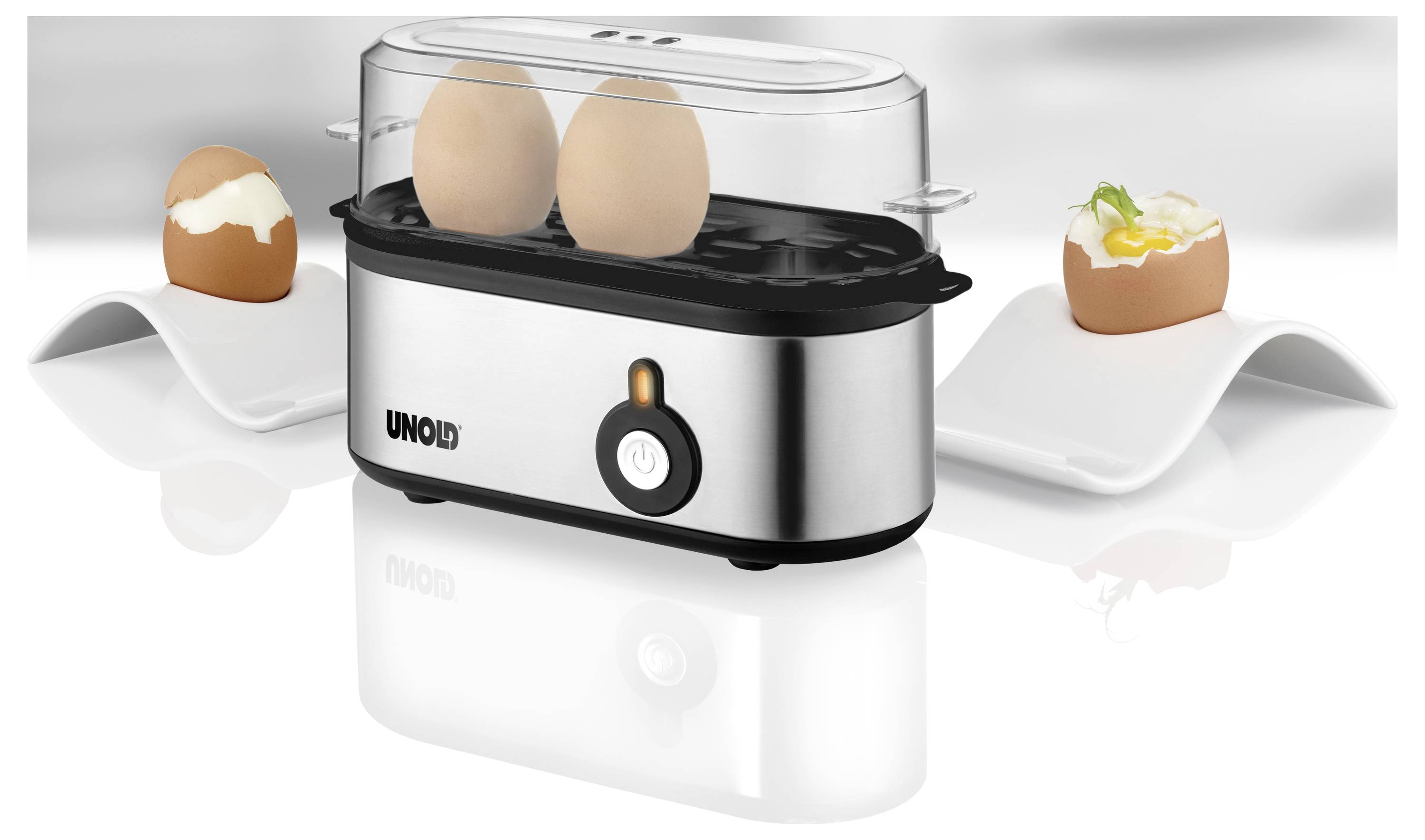 An egg cooker with a transparent lid is steaming two eggs, flanked by two half-cracked eggs in holders, one garnished with herbs.