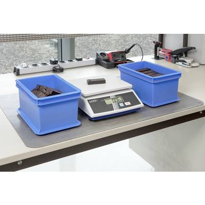 Electronic scales on a table with two blue containers. One container contains parts, the other is empty. The display shows 0.405 kg.