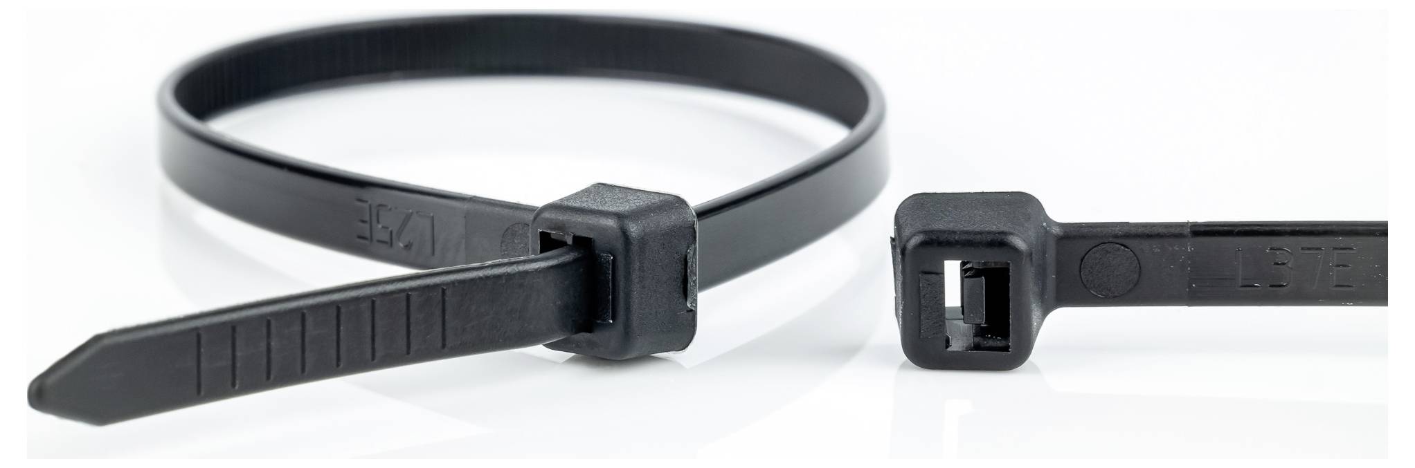A black zip tie is shown in a circular loop, with another zip tie lying open next to it, highlighting its locking mechanism.