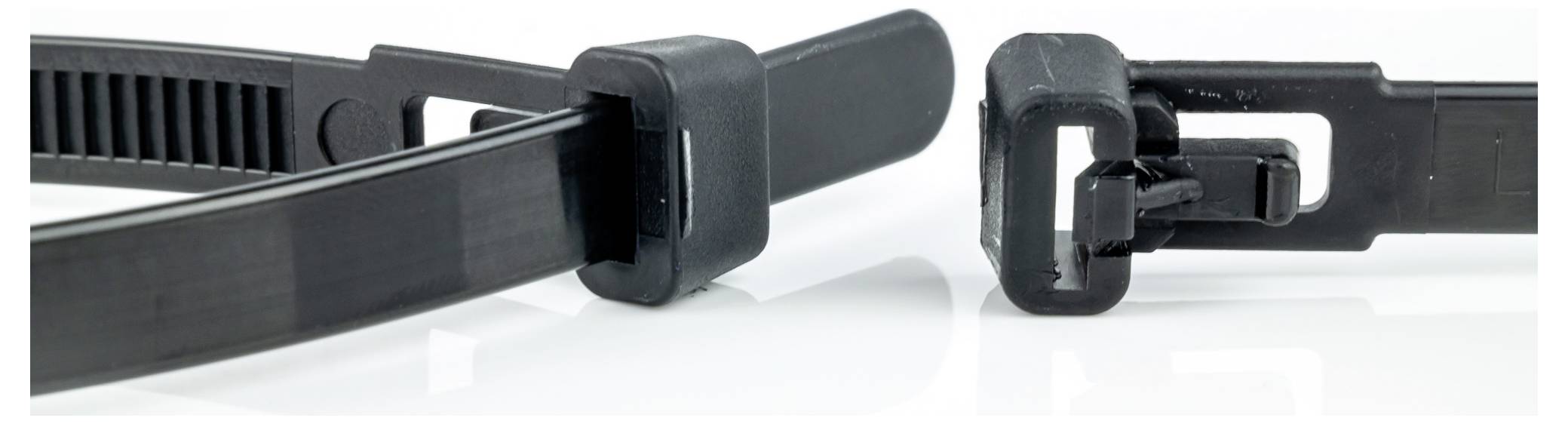 Black plastic zip ties with locking mechanisms, shown open and ready for use on a reflective white surface.