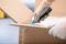 A person wearing gloves is opening a cardboard box with a craft knife.