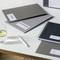 A desk with documents, notebooks and a glass of water. A folder is labelled 'Marketing Controlling Budget'. A ballpoint pen lies next to the documents.