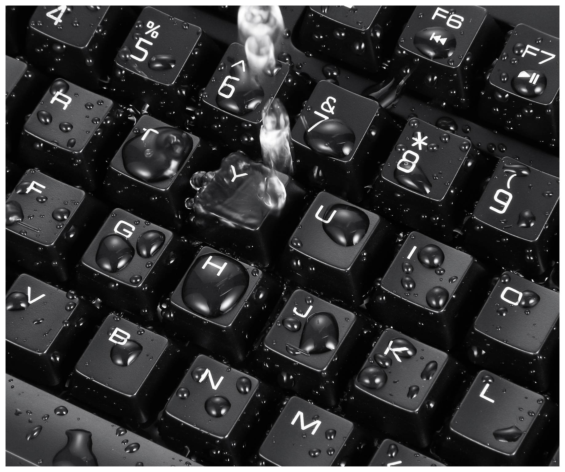 Water is being poured onto a computer keyboard, with the keys visibly wet. This demonstrates the keyboard's resistance to liquids.