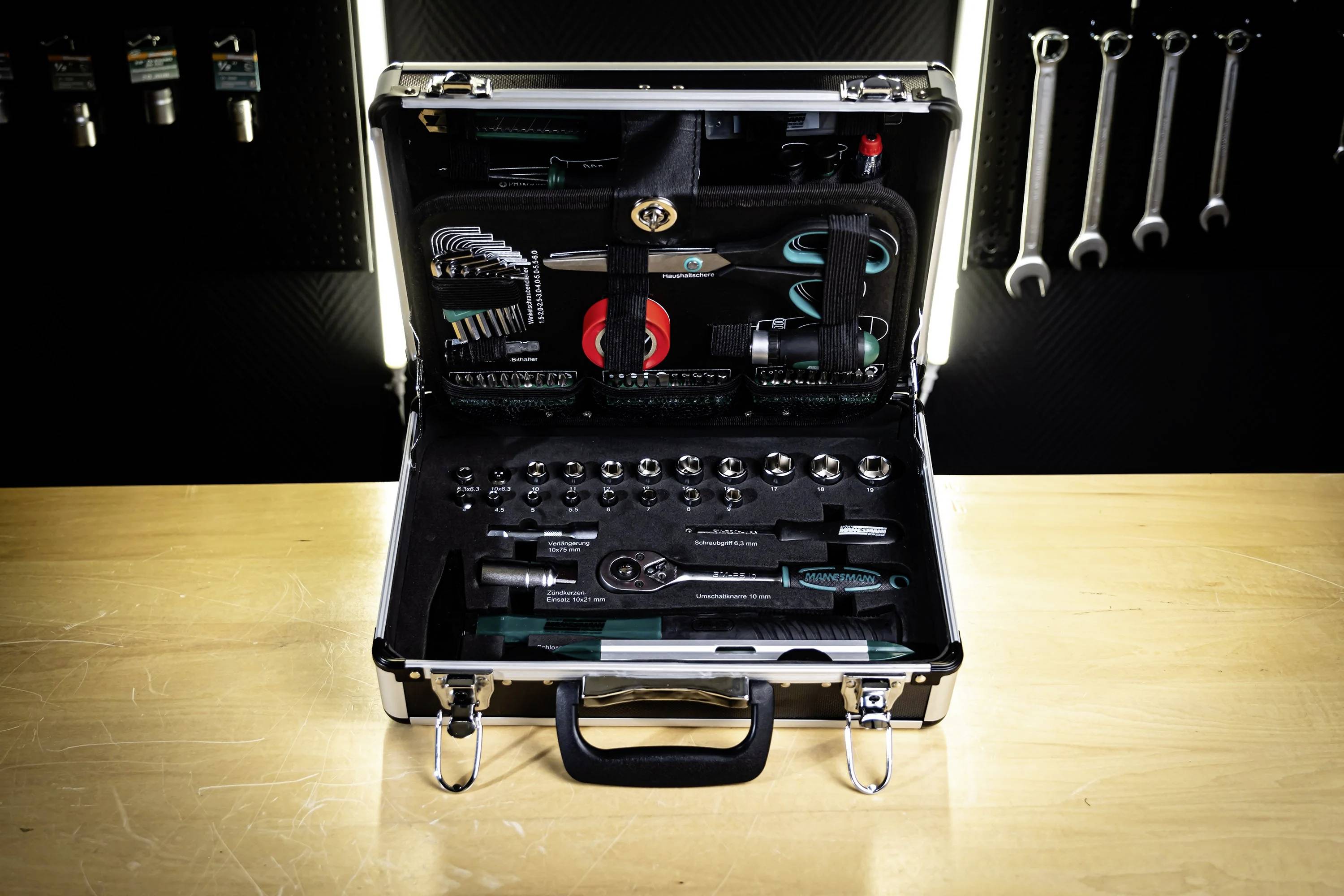 A spanner set in an open toolbox on a wooden table, displaying various tools including ratchets, socket wrenches, and bits.