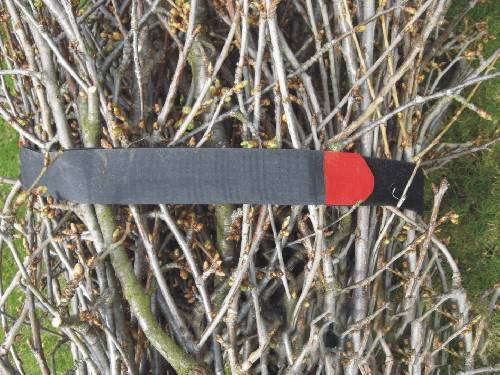 A handcrafted wooden bird figurine with a black body and red details is nestled amongst a bundle of bare branches.