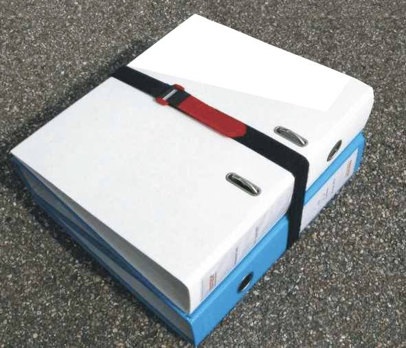 Two ring binders, a white one on top of a blue one, secured with a black strap on an asphalt surface.