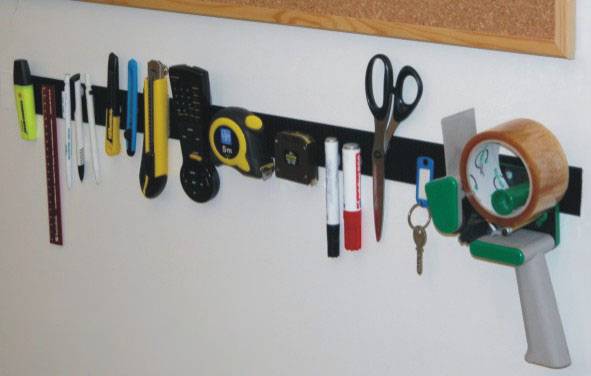Tools and stationery hang on a wall rail: highlighters, pens, tape measure, scissors, roll of tape, and keys.