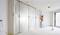 A tradesman is securing a plastic sheet to a wall in an empty room. The sheet protects against dust and dirt.