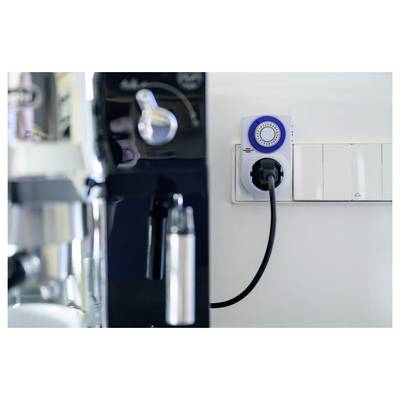 Electric coffee machine plugged into a wall timer outlet in a kitchen, indicating scheduled power control.<br>
