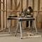 A person is working with a mitre saw on a table in a woodwork workshop. Safety equipment is being worn.