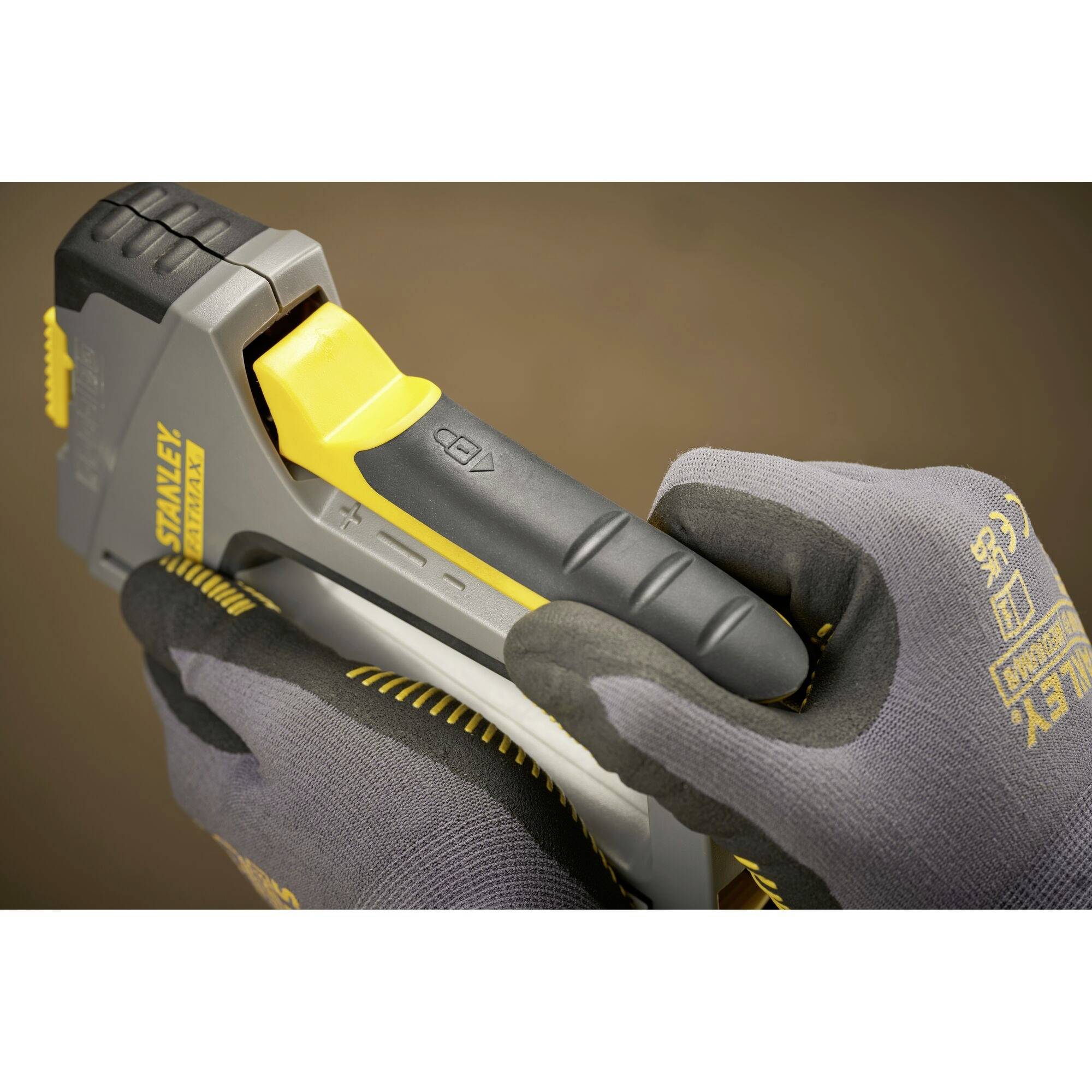 Human hands in work gloves hold and operate a nail gun used for construction or DIY projects.