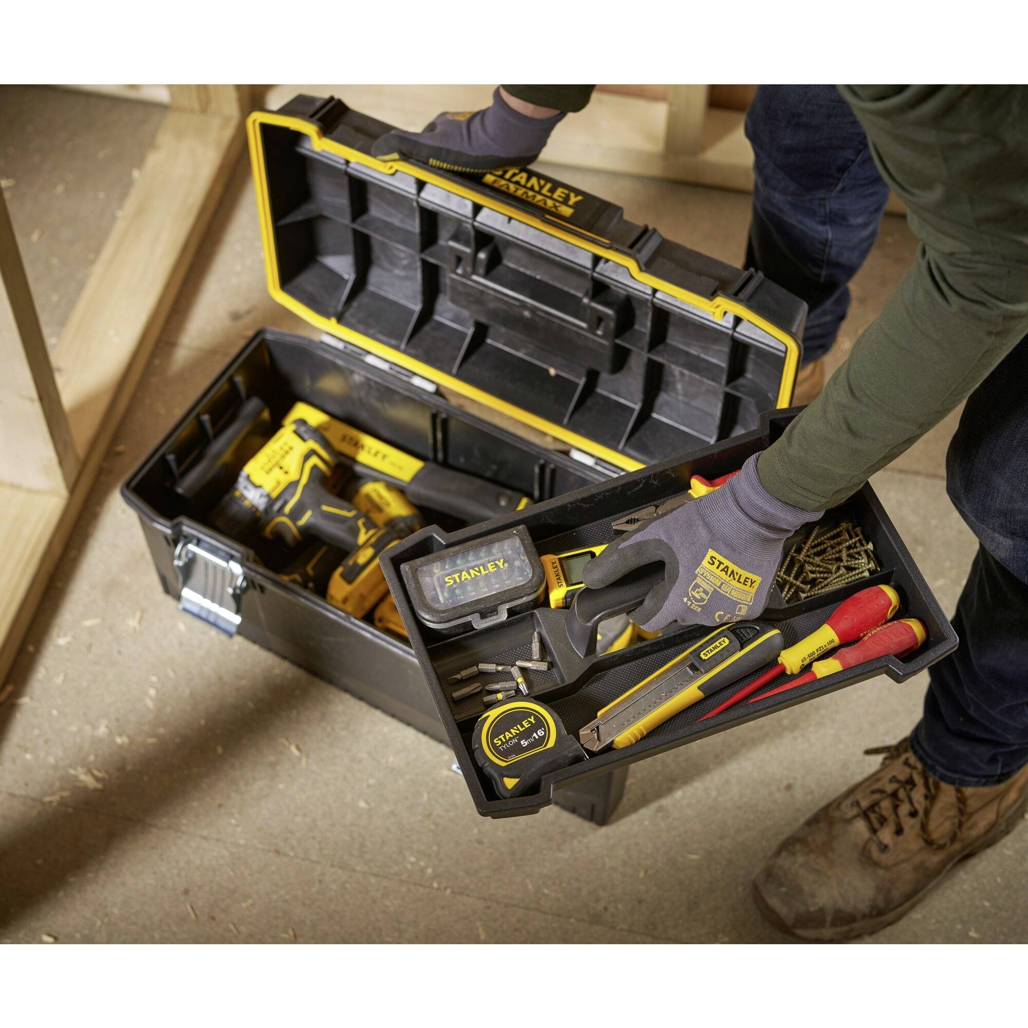 An opened toolbox contains various tools, including a tape measure, a hammer and a cordless drill.