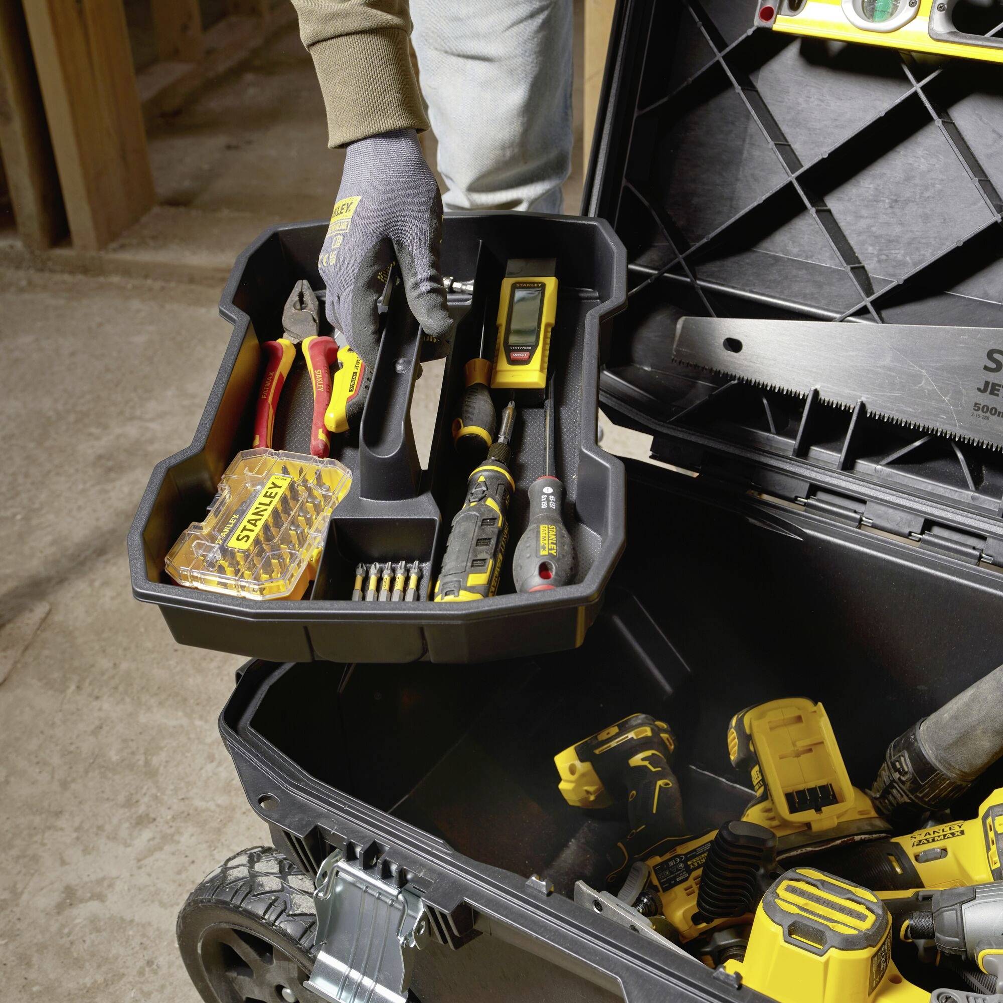 A tradesman opens a tool case filled with various tools, including a saw, tape measure, and drill.