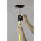 'A person attaches a yellow telescopic pole to the ceiling to secure a mounting bracket. Hands are turning the tensioning device.'